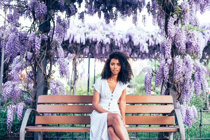 Happy young black woman sitting surrounded by flowers