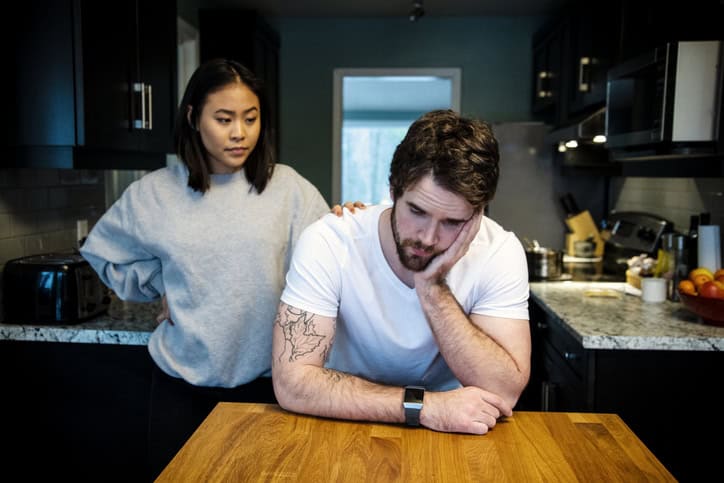 A young man suffering from depression at home in his kitchen.