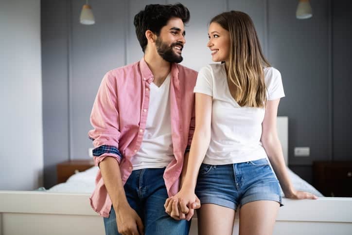 in love couple holding hands on bed