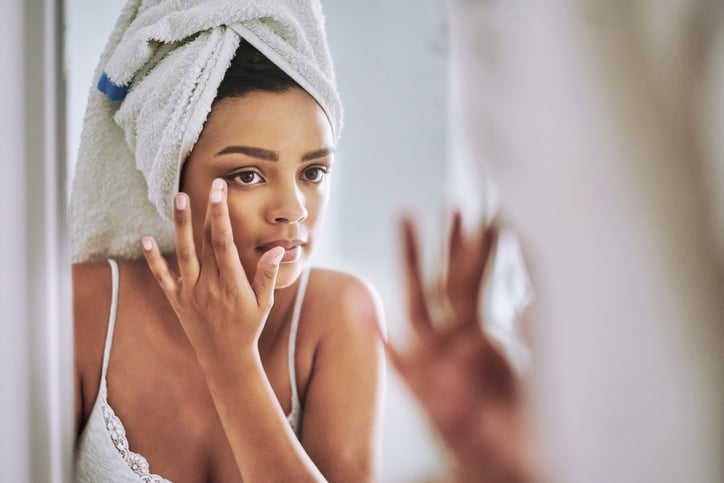 Woman applying makeup in the mirror.