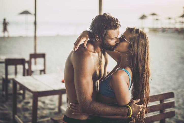 Young loving couple kissing during summer day on the beach.
