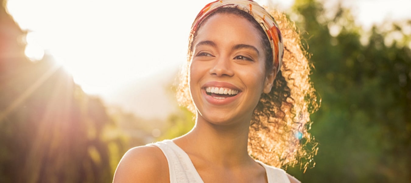 Woman on a walk outside smiling.