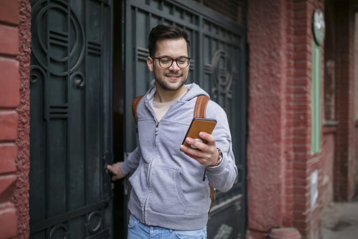smiling guy texting leaving apartment