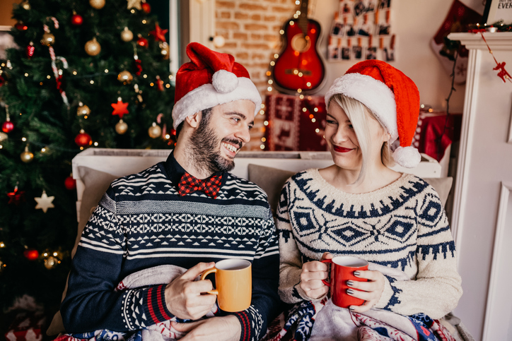 Couple drinking tea in front of a Christmas tree