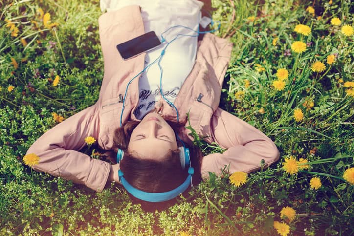 woman laying in flowers listening to music