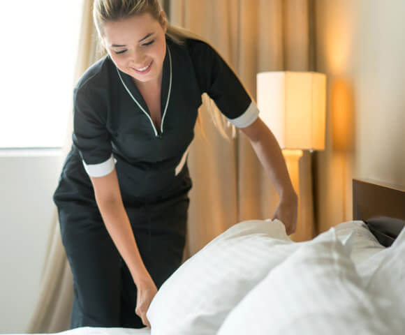 Housekeeper making the bed at a hotel.