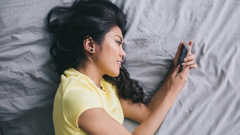 asian woman texting in bed