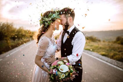 couple in wedding clothes kissing roadside