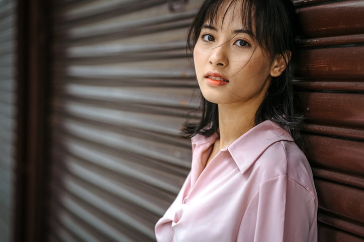 asian lady standing beside a wall