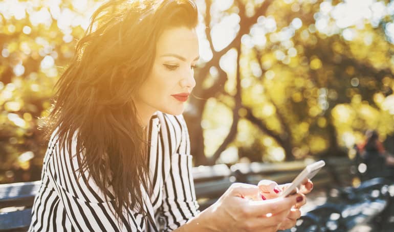 woman in sunset looking at smartphone