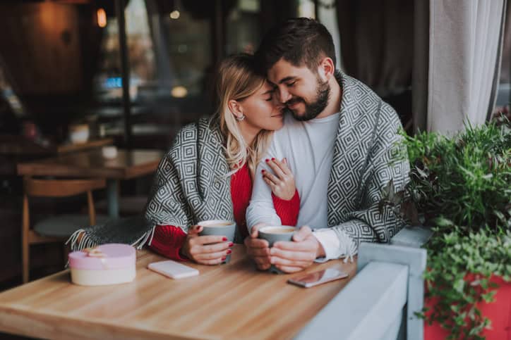 couple having coffee wrapped in blanket