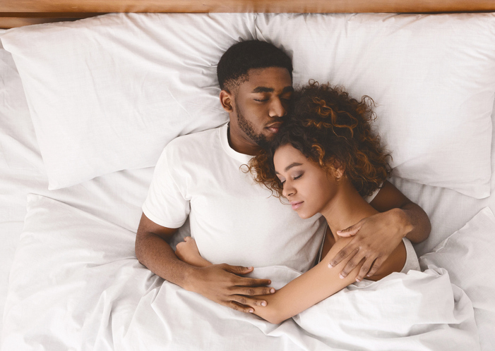 Lovely black couple lying in white bed, couple sleeping together, top view