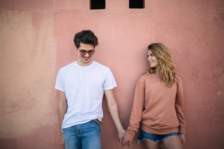 couple leaning against a pink wall