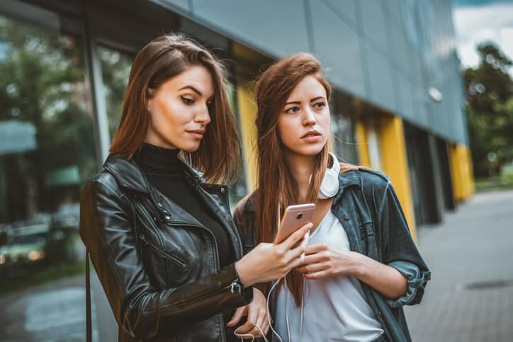 two women looking at their smartphone