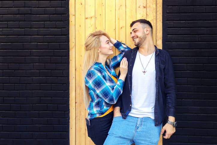 couple smiling together near a wall
