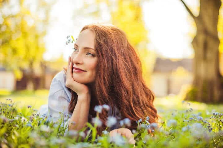 beautiful redhead woman laying in grass