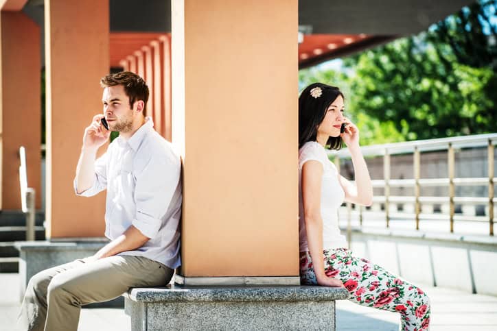 couple sitting back to back on a platform