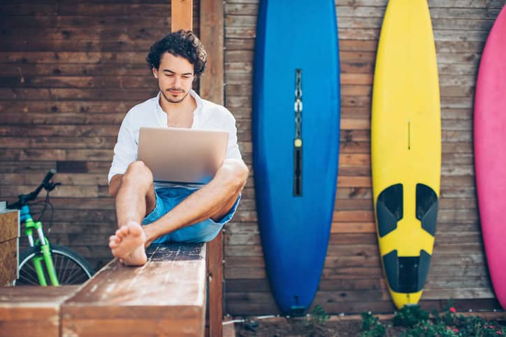 man with surfboards and laptop