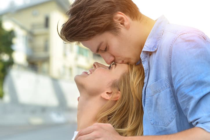 man kissing woman on the forehead