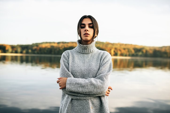 serious woman with arms crossed by water