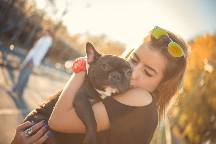 woman holding and kissing her dog