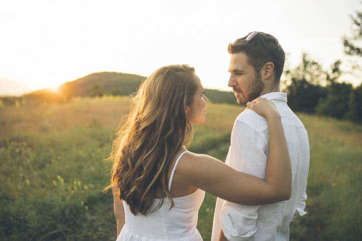 couple being intimate outside in the sunset
