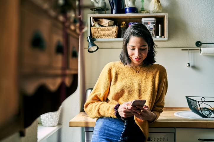 young woman texting in kitchen