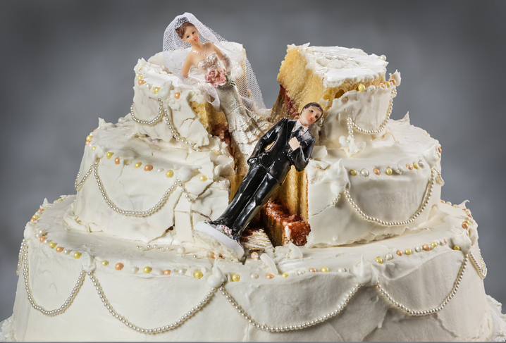 Bride and groom figurines collapsed on a ruined wedding cake.