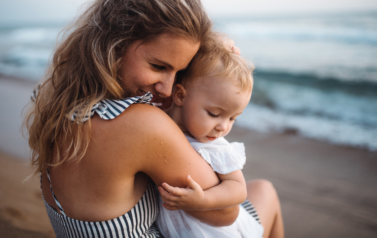 woman holding child on beach