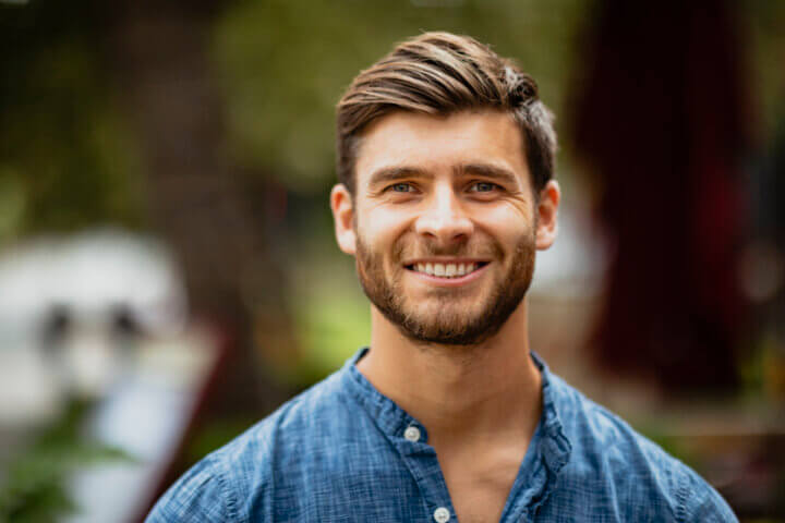 A portrait of a mid adult man smiling while looking at the camera.