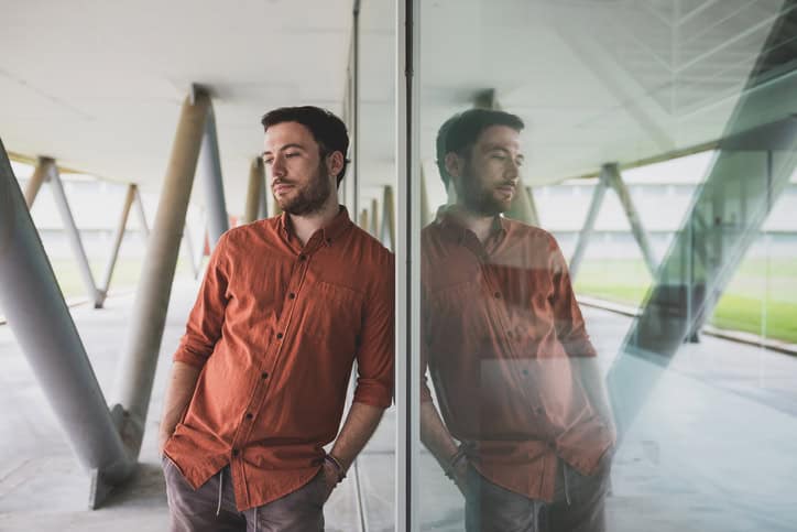 Portrait of stylish handsome young man reflected on glass wall.