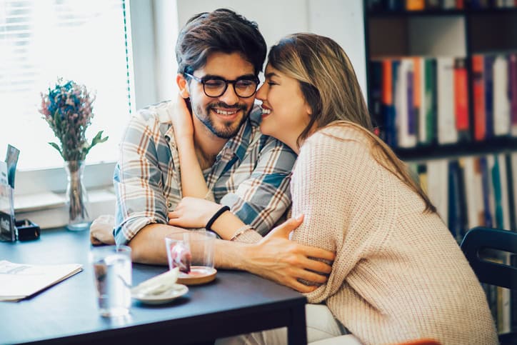 woman whispering into man's ear