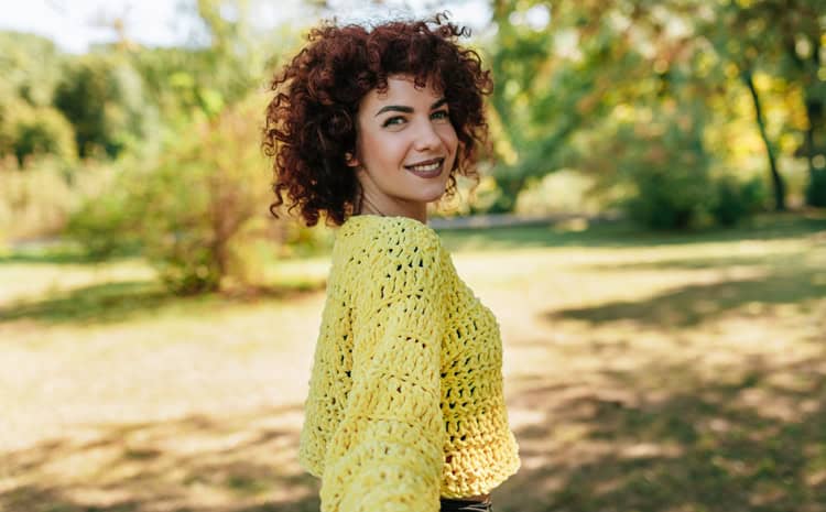 curly haired woman yellow top outside