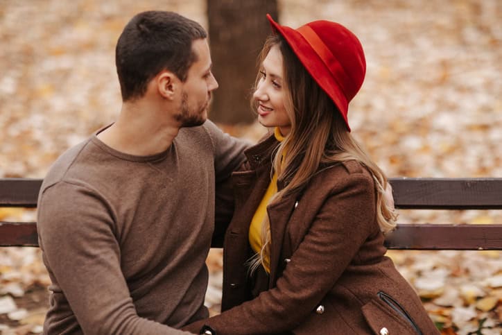 couple sitting on a bench woman in red hat