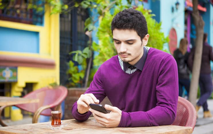 young man texting at a table