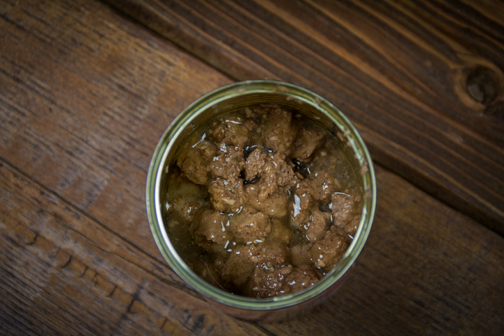 Open can of beef pet food on a wooden table