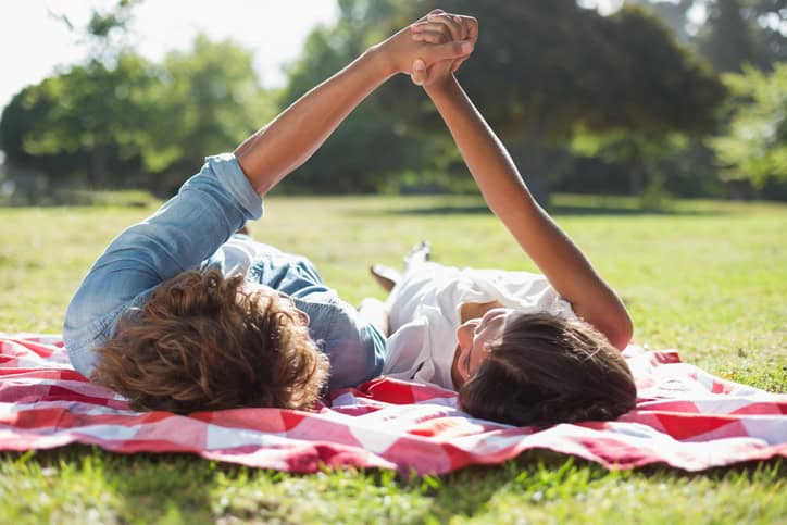 couple laid on a blanket holding hands