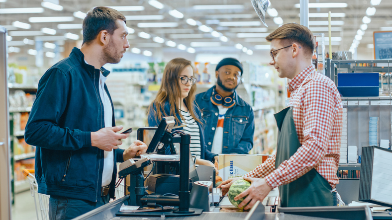 At the Supermarket: Checkout Counter Customer Pays with Smartphone.