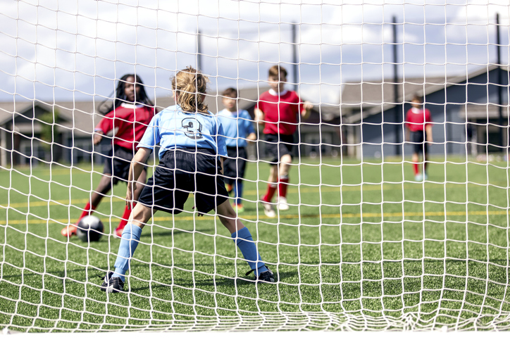 A mixed gender soccer team makes a goal attempt.
