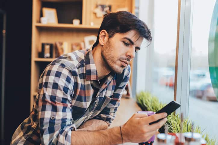 man texting at a cafe