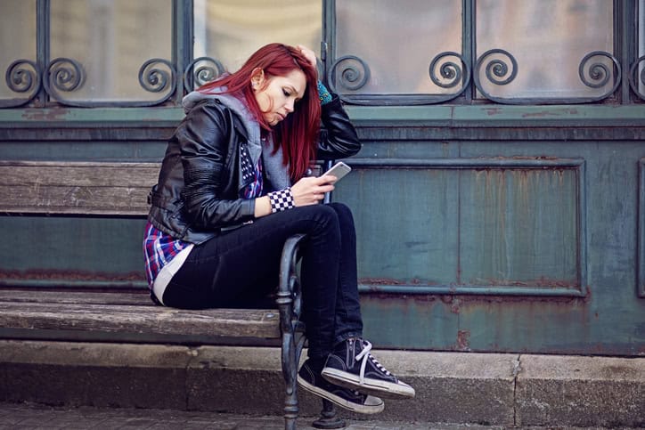 woman with red hair on steps texting