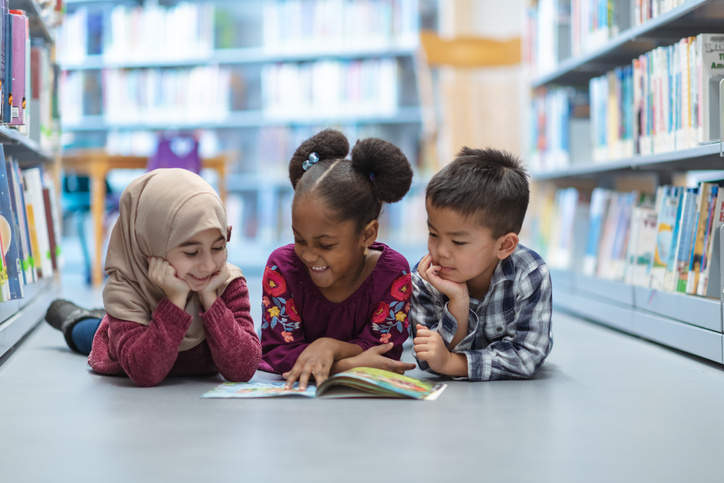 three children reading in a library
