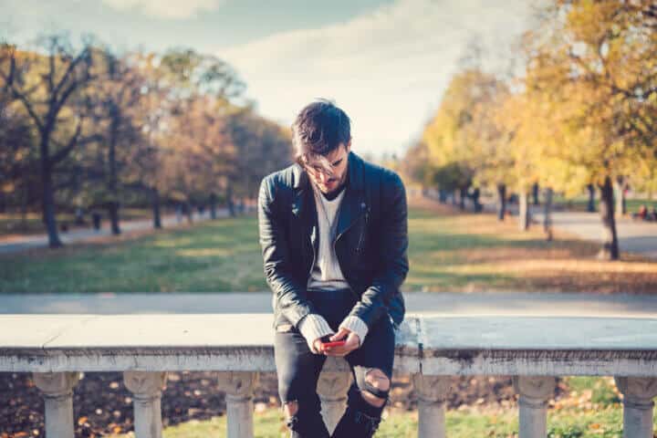 man sitting on a bridge texting