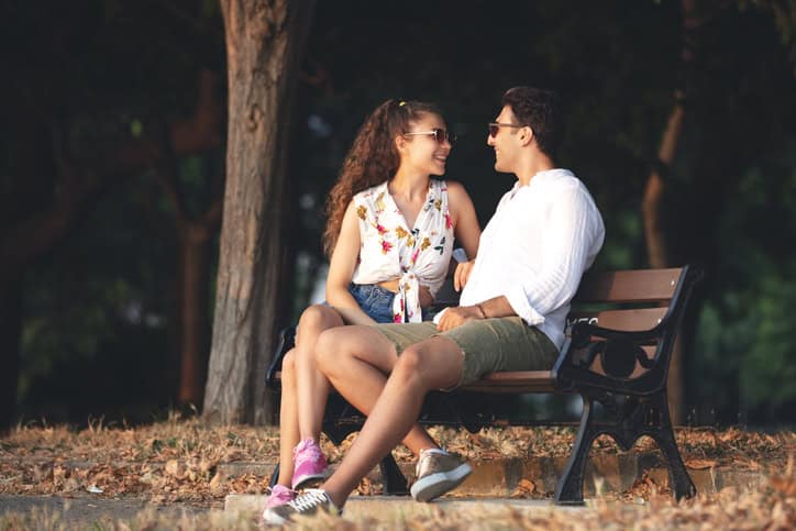 young couple sitting outside on a bench talking