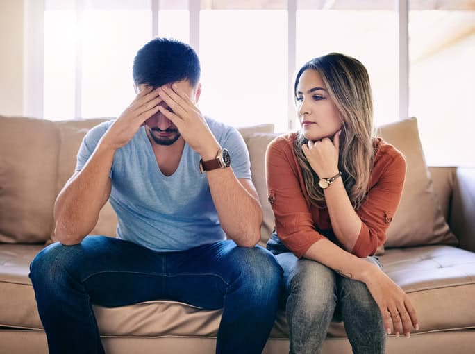 couple sitting sofa unhappy