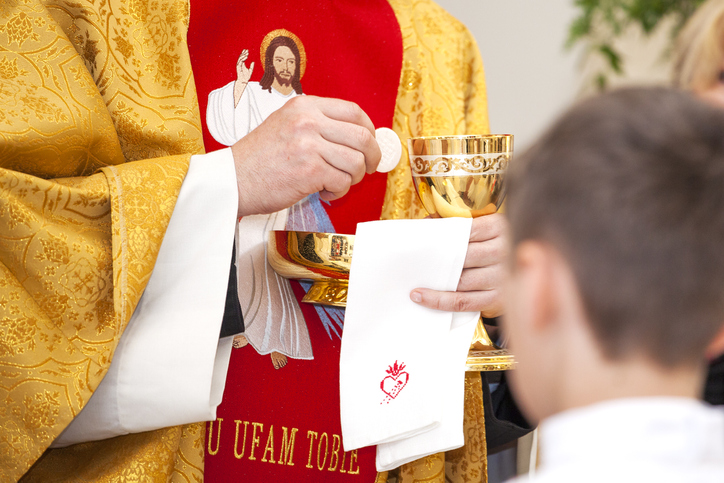 Priest gives child communion.