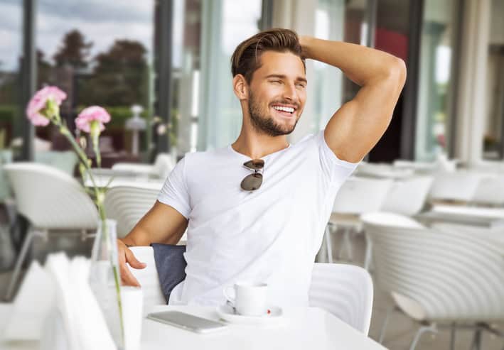 handsome model guy flexing at outdoor cafe