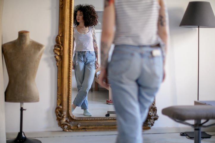 Women looking in the mirror at her body.