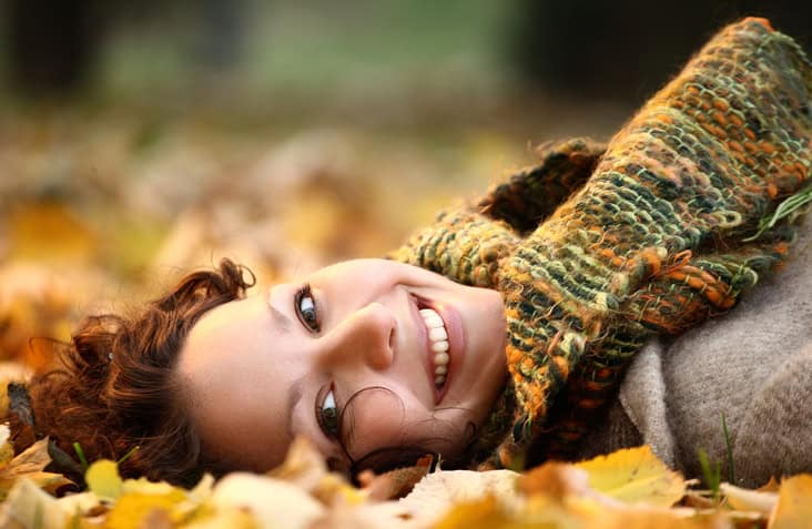 woman laying in autumn leaves