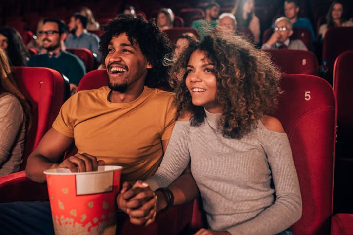 Man and woman holding hands at cinema.